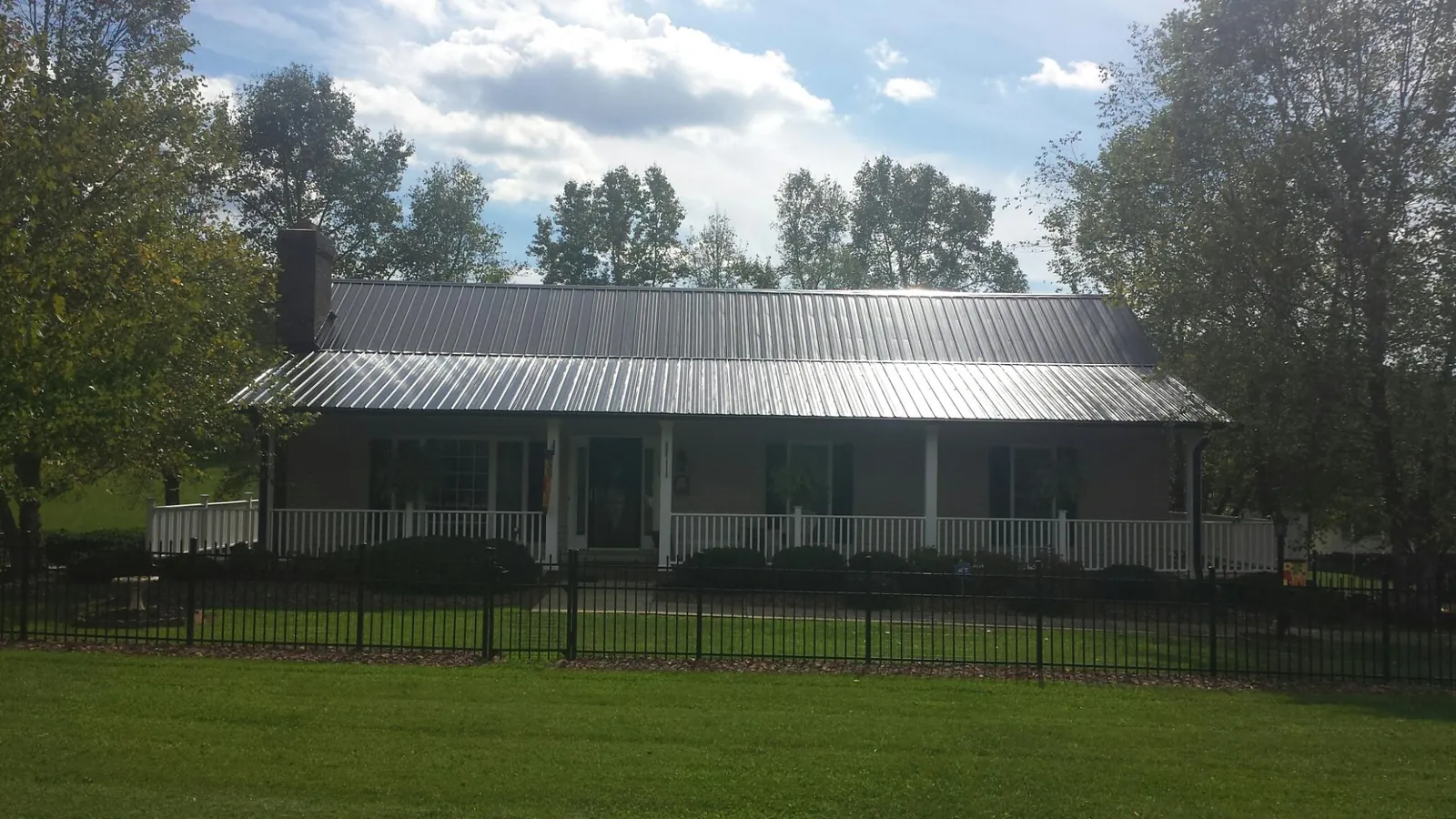 Gray metal roof on a brick ranch with a full width front porch — Gutter Guard Installation work by our crew in Kiowa