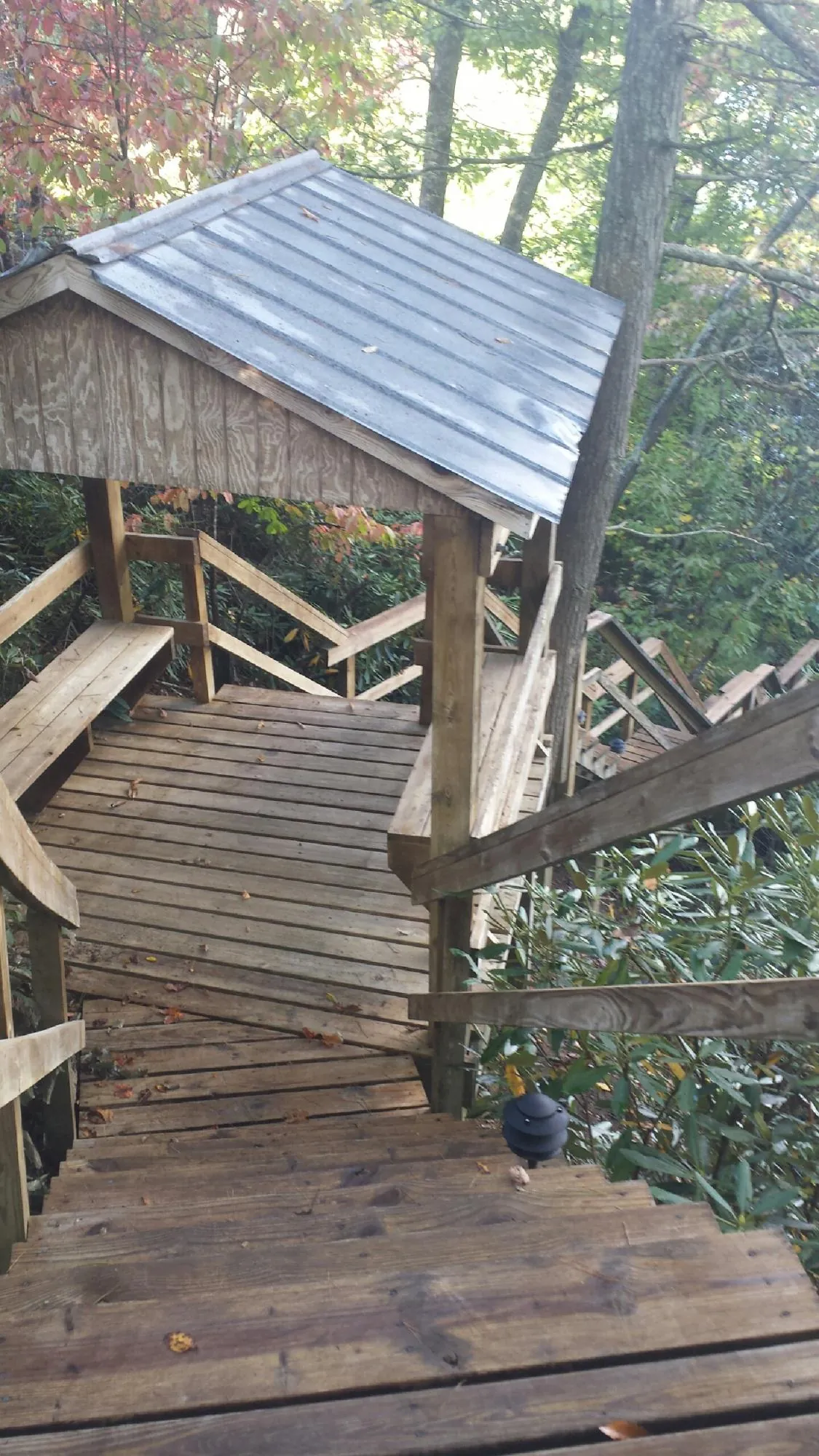 Metal roofed shelter over wooden steps on a wooded walkway — Skylight Repair & Installation work by our crew in Kiowa