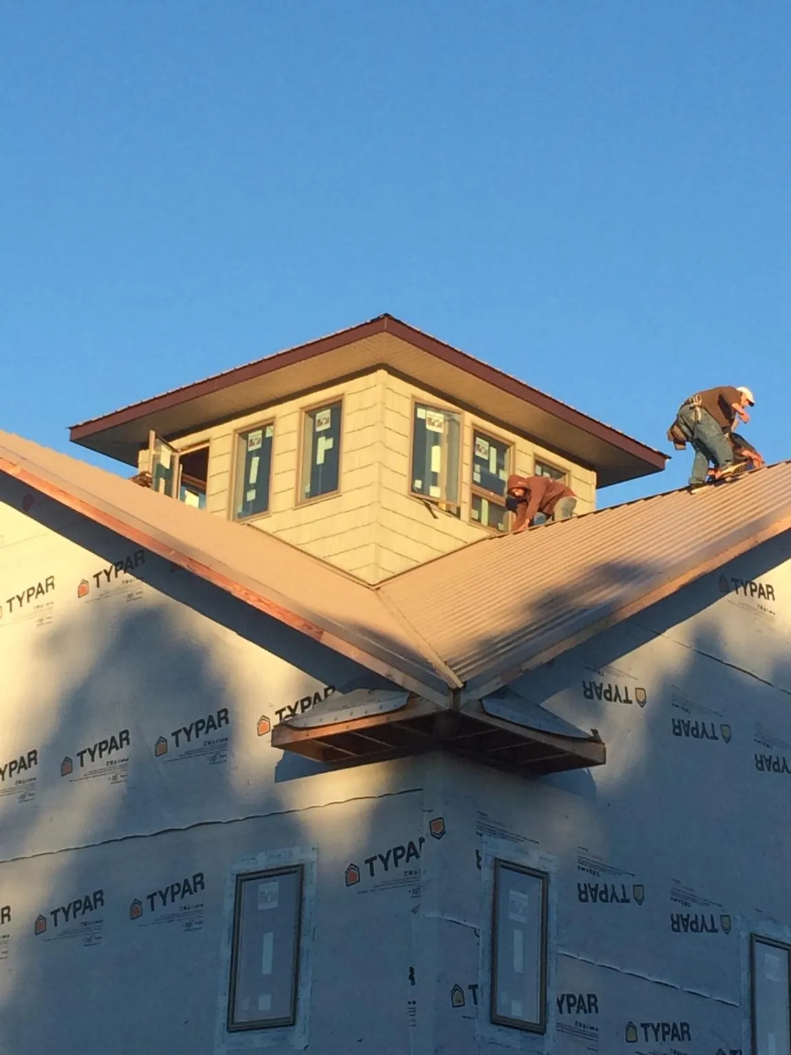 Roofers working around a rooftop cupola on a new metal roof at sunset — Roof Waterproofing in Kiowa by Roofing Brothers